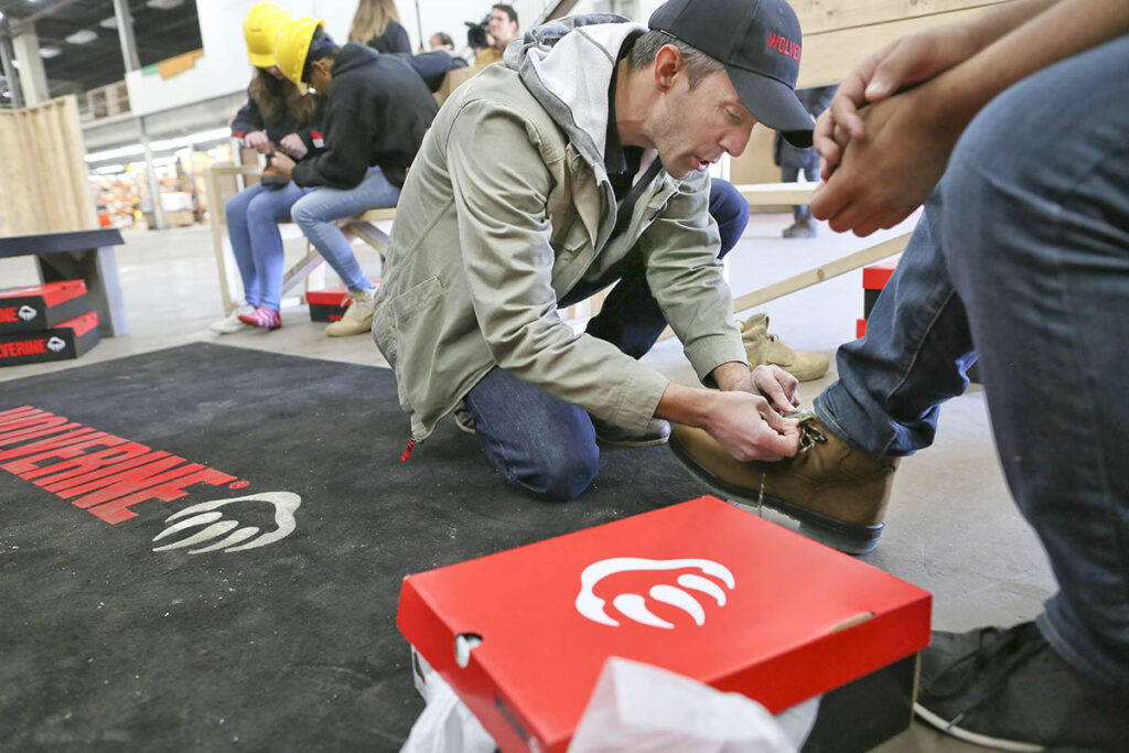 Josh Cox from Wolverine helps a student try on boots